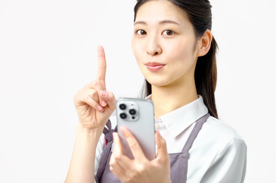 スマホを持ち指さしポーズする主婦