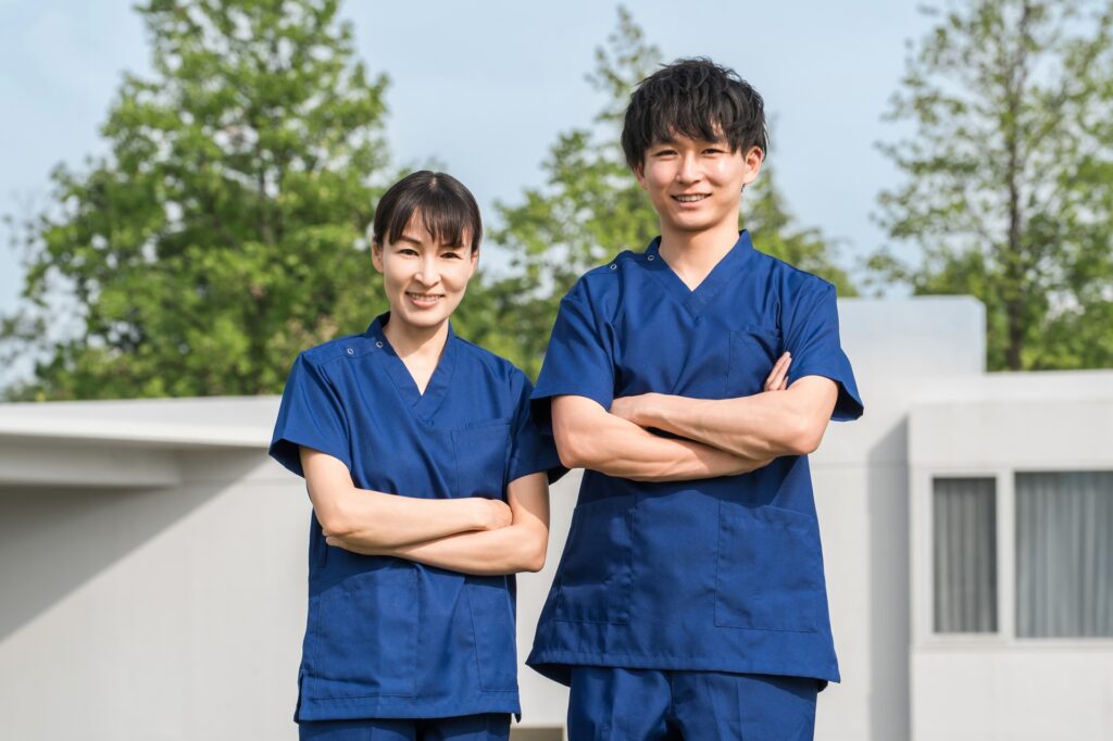 病院・施設の前にいる医療従事者の男女