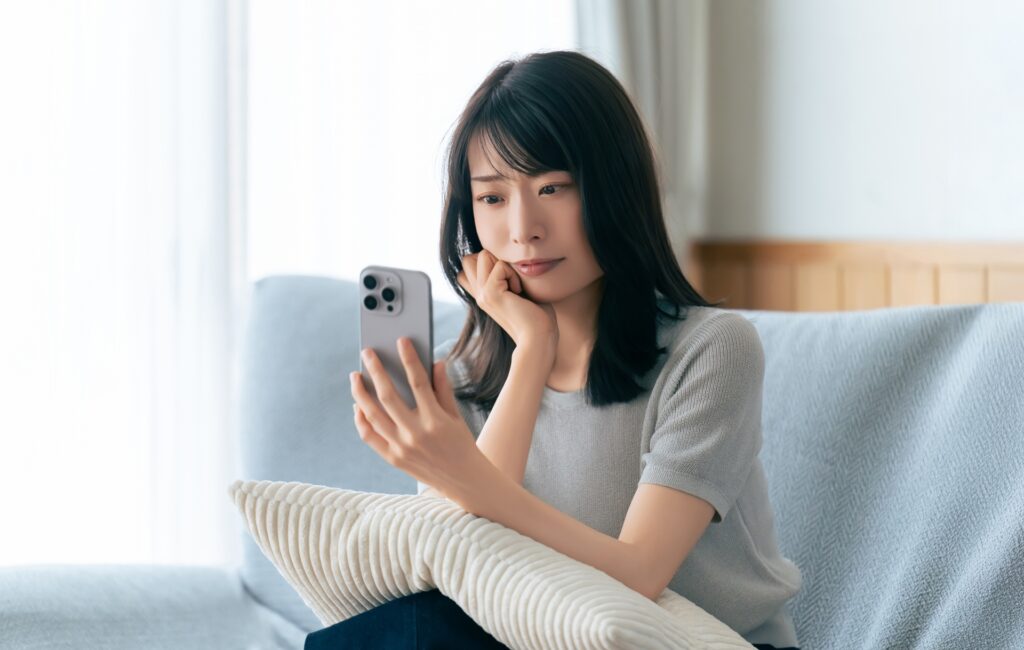 スマホを見ながら考えごとをする女性