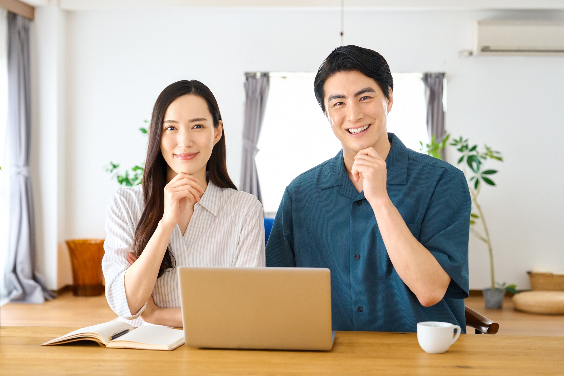 パソコンで相談し笑顔を見せる若い夫婦
